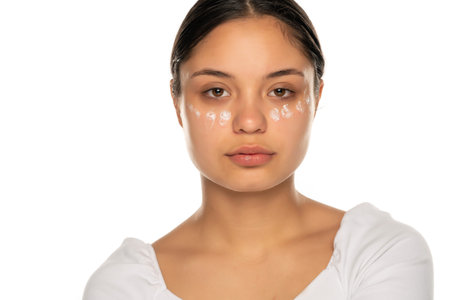a young serious woman posing with facial  cream on a white background