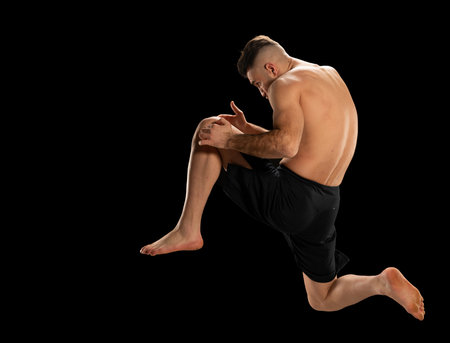 MMA fighter in black shorts in a fighting position on a black background