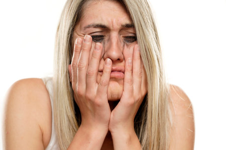 portrait of a beautiful despered woman with smudged makeup on a white backgroundの写真素材