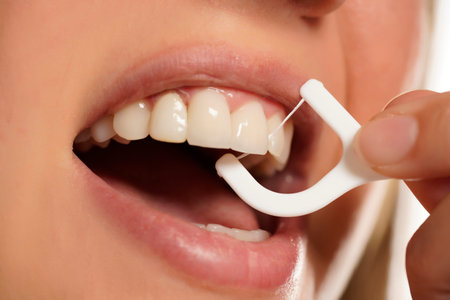 Closeup of a woman cleaning her teeth woth floss
