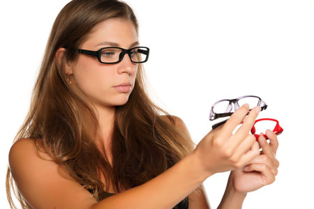 a young beautiful woman compares glasses to a white background