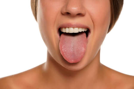 young woman sticking out her tongue on white backgroundの写真素材