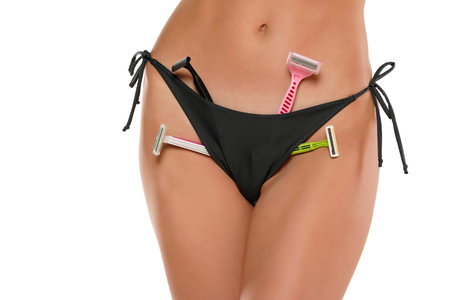 Woman posing with a razors in her panties on a white background