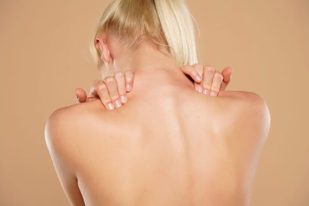 Woman with shoulder pain on a beige background