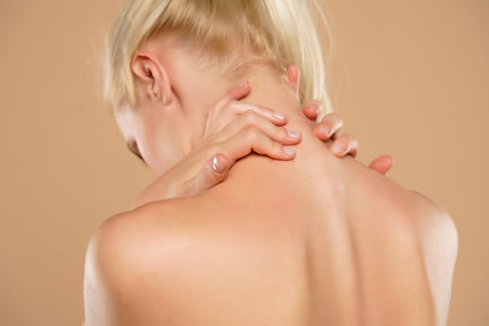 Woman with neck pain on a beige backgroundの写真素材