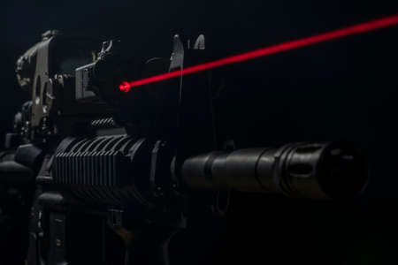 Optical sight and laser device with a red beam on the M4 rifle on dark backgroundの写真素材