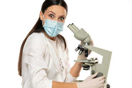 Portrait of shocked female scientist with microscope on a white background