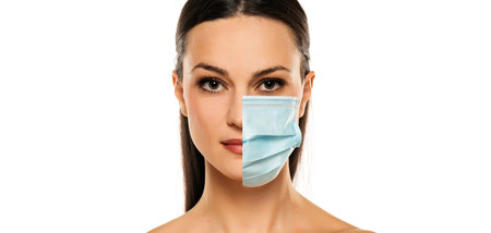 Studio portrait of young shirtless woman wearing a face mask, looking at camera, close up on white...