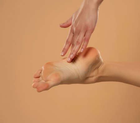 Foot Heel Skin Care, Woman Touch Healthy Feet Body by Hand, Leg Isolated over Beige Background.の写真素材