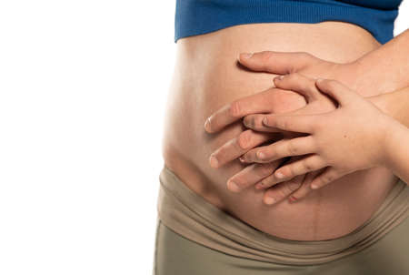 Pregnant woman and her husband and son holding hand together, 3 hands holding baby inside a pregnant woman, love of family.の写真素材