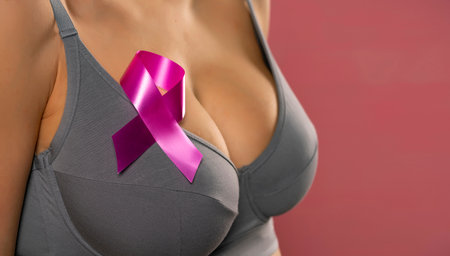 Close up young woman in gray bra with cancer awareness ribbon on pink backgroundの写真素材