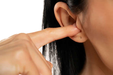 Closeup macro shot of woman putting fingers on the ears on white background.の写真素材