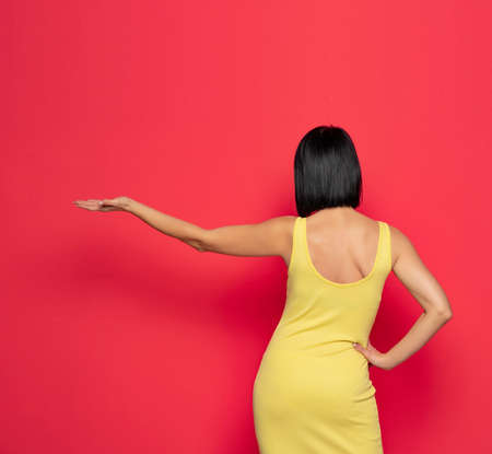 Rear view of a  woman over isolated red background presenting an ideaの写真素材