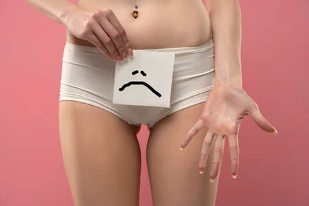 Woman holding paper with sad emotion over her panties.Health hygiene sexual education concept.の写真素材