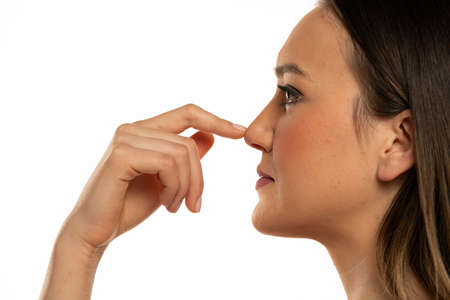 Young woman touches her nose with her finger on a white background.の写真素材