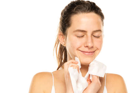 A young happy woman removing makeup with the wet tissues  on white background.の写真素材