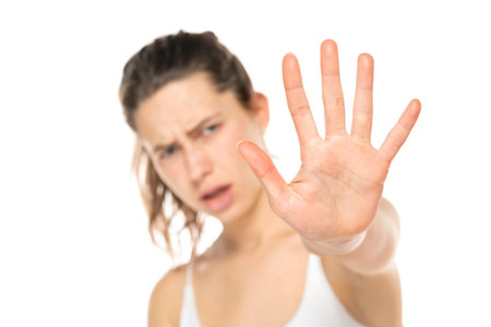 rejecting young woman saying stop, no, halt with hand gesture on a white background.