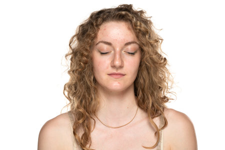 Young blond women with long curly hair and problematic skin. Eyes closed.の写真素材