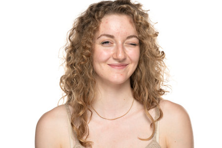 Winking blond women with long curly hair and problematic skin.の写真素材