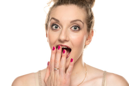 Young blond surprised woman with curly tied hair and makeup posing on white background.の写真素材