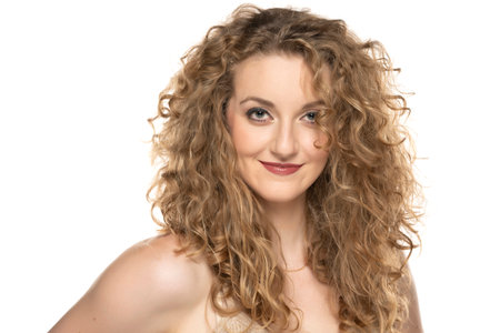 Attractive blonde woman with curly beautiful hair smiling on white background.の写真素材