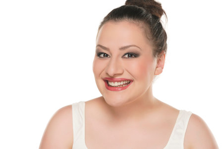 Portrait of a young happy chubby woman with makeup on a white studio background.の写真素材