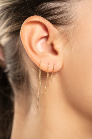 Female ear with three ear chaines. CLose up.