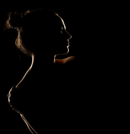 Sensual portrait silhouette of beautiful woman in backlight on a black studio backgroundの写真素材