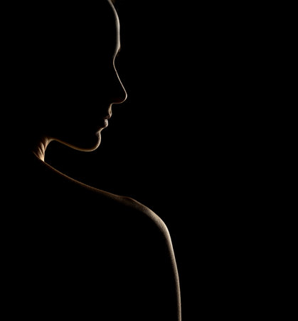 Sensual portrait silhouette of beautiful woman in backlight on a black studio backgroundの写真素材