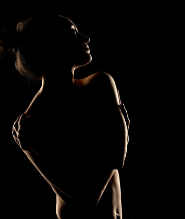 Sensual portrait silhouette of beautiful woman in backlight on a black studio backgroundの写真素材