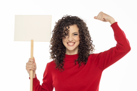 Young curly happy woman holding blank sign on white studio background.の写真素材