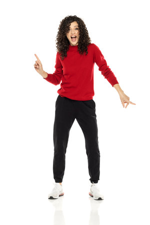 Young curly happy woman dancing on white studio background.の写真素材