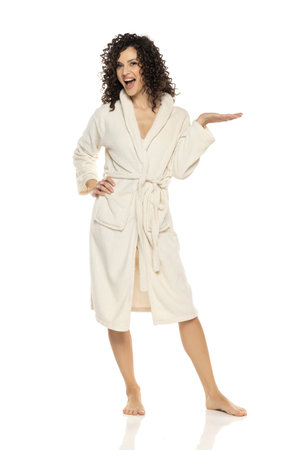 young happy woman posing in bathrobe and holding imaginary objeect on a white studio backgroundの写真素材