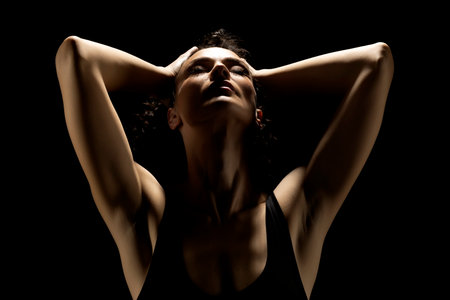 Portrait of a woman in the shadow, hold her head , closed eyes on a black studio backgroundの写真素材