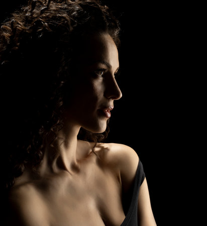 Sensual portrait silhouette of beautiful curly woman in backlight on a black studio backgroundの写真素材