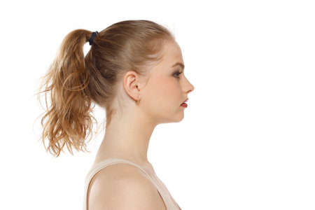 Profile, side view of beautiful serious blonde woman with tied hait on a white studio backgroundの写真素材