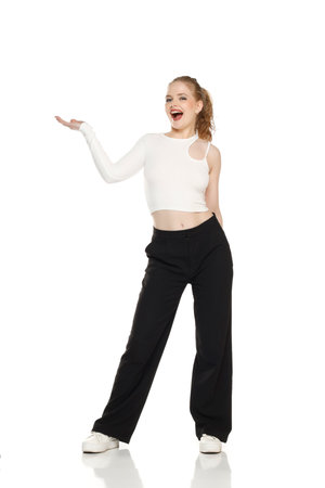Young happy blonde woman with tied hair  over isolated white studio background holding copyspace imaginary object on the palm to insert an adの写真素材