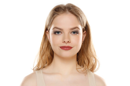 Portrait of young beautiful blonde woman with makeup on white studio backgroundの写真素材