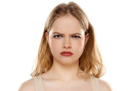 Suspicious annoyed young blond woman with distrustful face looking at camera, skeptical sarcastic girl feeling cautious dubious distrusting isolated on white studio backgroundの写真素材