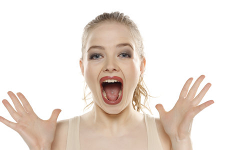 Portrait of young beautifu happy blonde woman with makeup and tied hair on white studio backgroundの写真素材