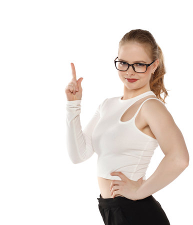 Smiling beautiful blond woman pointing finger upward to empty space on a white studio backgroundの写真素材