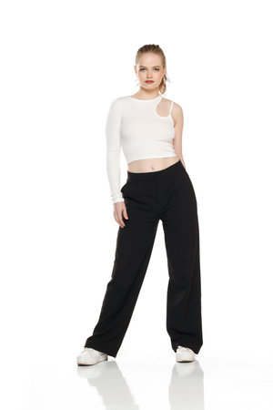 Front view of young blond woman in trousers and white blouse posing on white studio backgroundの写真素材