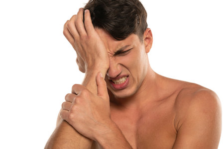 Closeup portrait of shirtless 20s man with eye pain isolated over white studio backgroundの写真素材