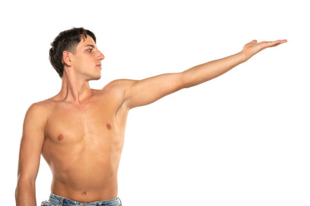 Muscular man with his arm outstretched. topless young fashion model with his hand in the air . Isolated on a white studio backgroundの写真素材