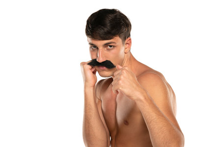 Young shirtless man with moustache in boxing stance on a white studio backgroundの写真素材