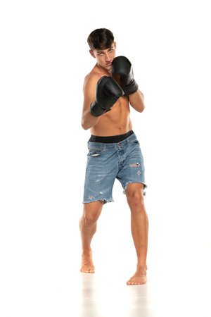 Young shirtless man with boxing gloves on a white studio backgroundの写真素材