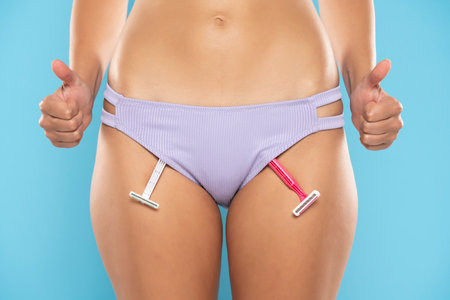 shaving blades in panties. girl health and intimate hygiene. Beautiful Woman's body with smooth soft skin in blue bikini panties with thumbs up. Epilation Concepts. blue studio backgroundの写真素材