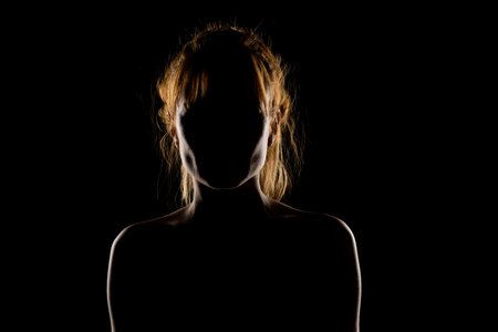 Silhouette of woman's head and shoulders, back light.の写真素材
