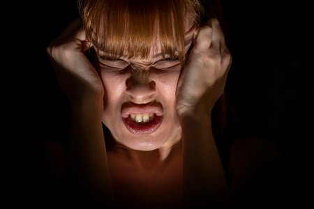 Portrait of mad and nervous young woman in the dark. Closed eyesの写真素材
