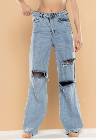 Woman showing slim body after sport trainings, healthy eating. Weight loss concept. Thin woman in big pants,  Slim girl wearing oversized pants on a beige studio backgroundの写真素材